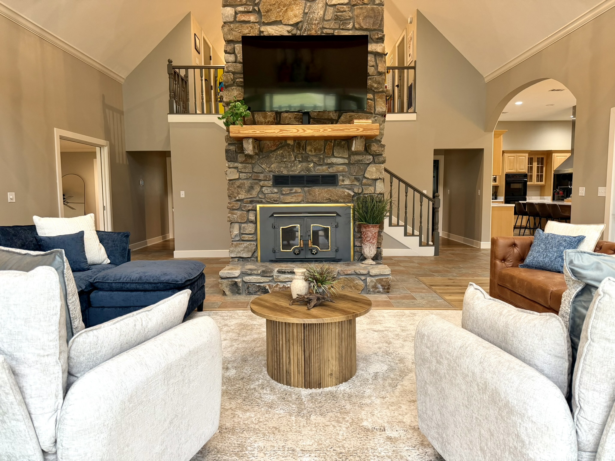 Living room featuring stone fireplace exposed beams and comfortable seating