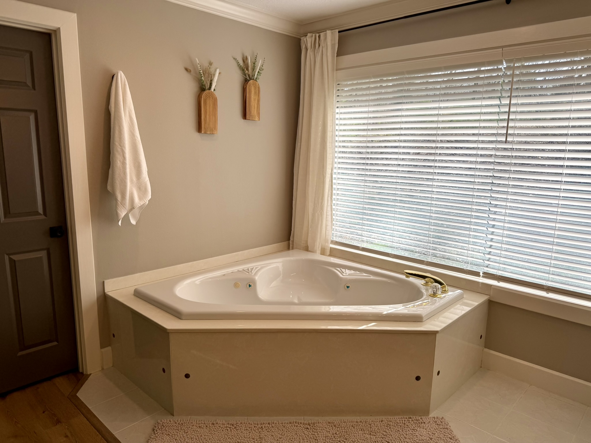 Primary en suite jetted corner soaking tub with natural light