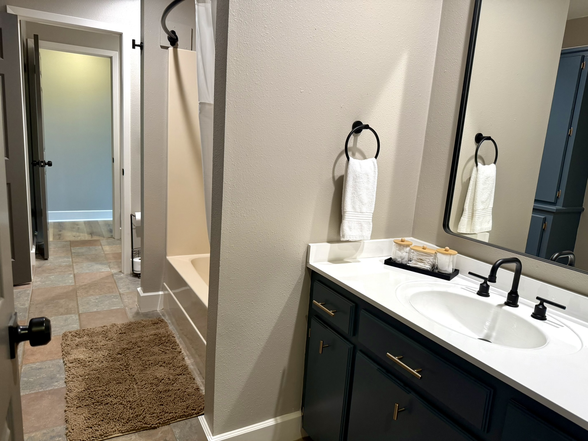 Jack and Jill bathroom with blue vanity black mirror and tub shower combo