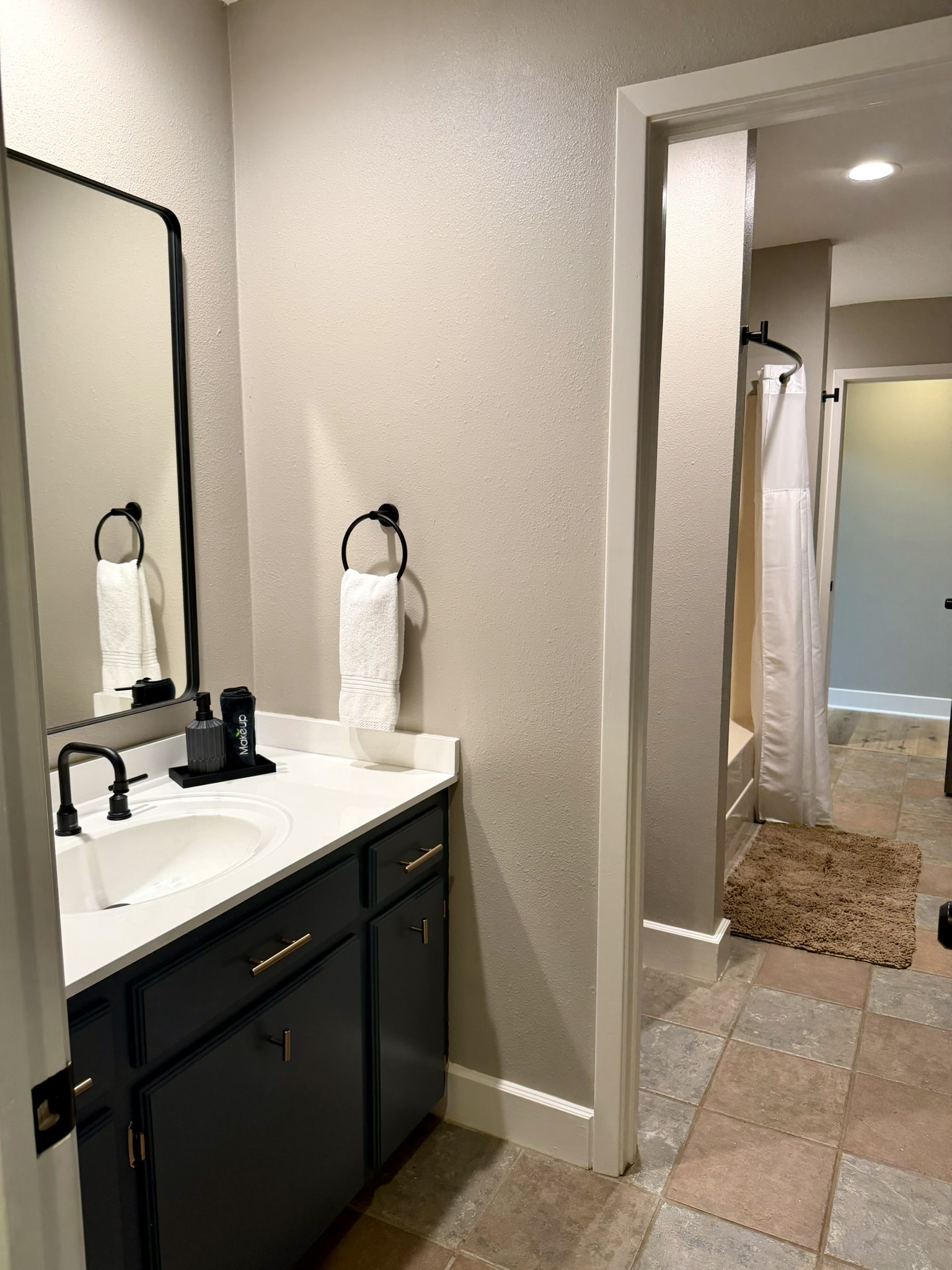 Jack and Jill bathroom vanity with black fixtures and doorway to shower