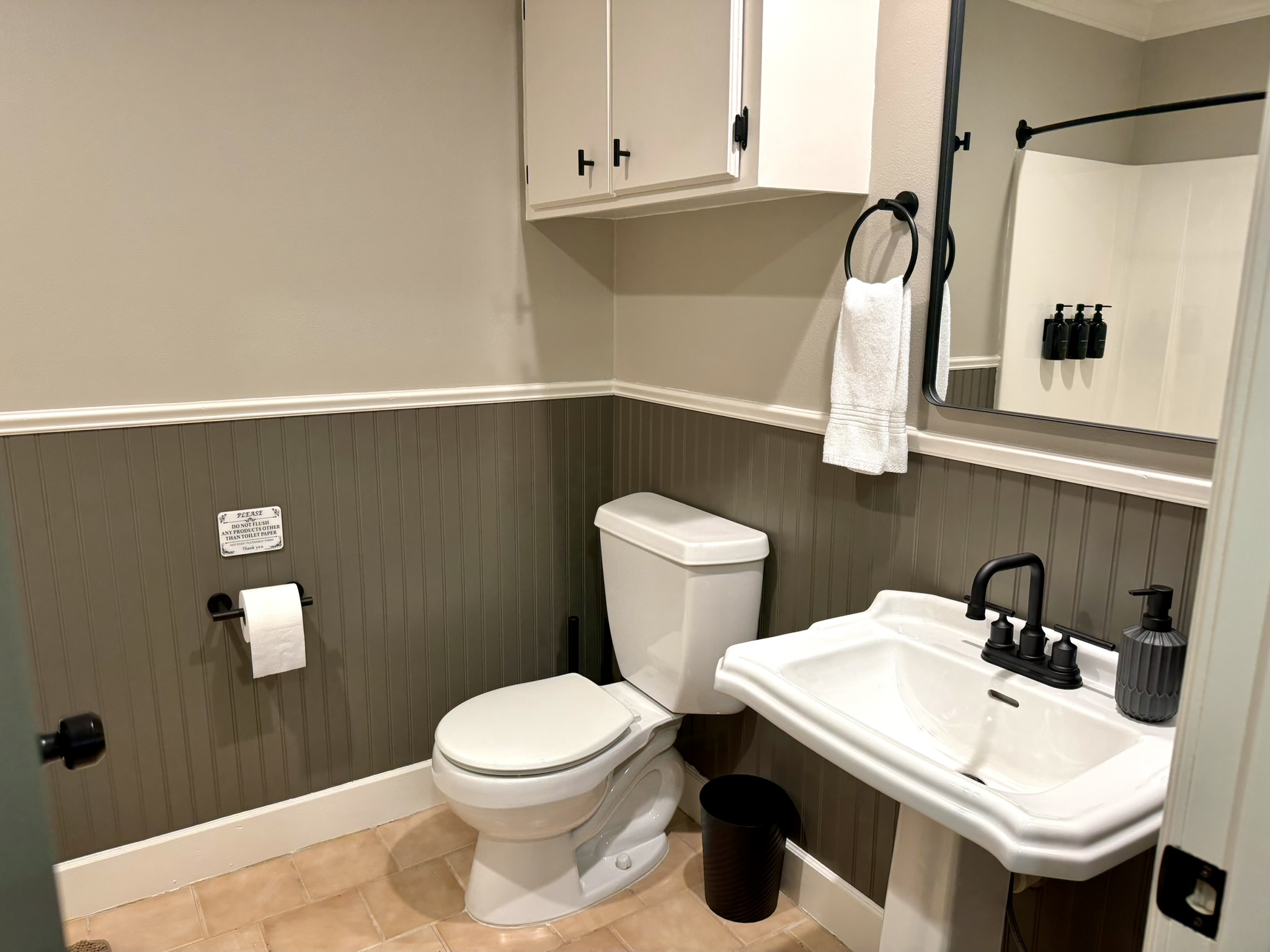 Half bathroom with green beadboard wainscoting pedestal sink and black fixtures