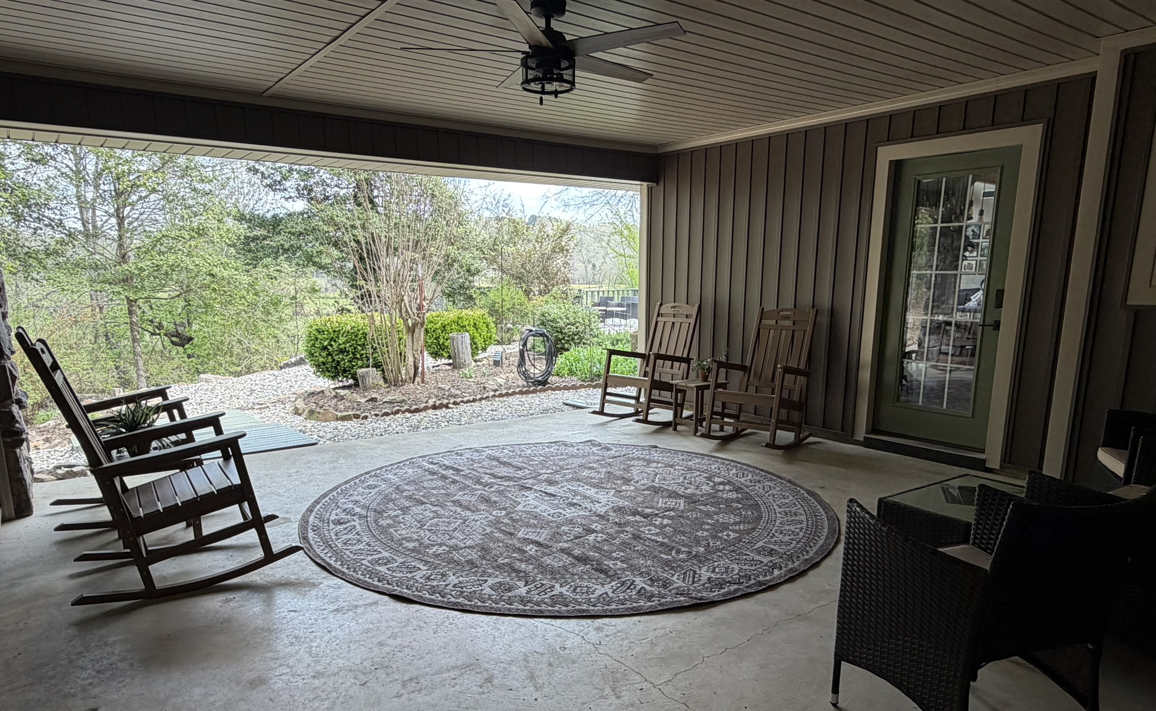 Covered breezeway porch with rocking chairs round rug and landscaped courtyard