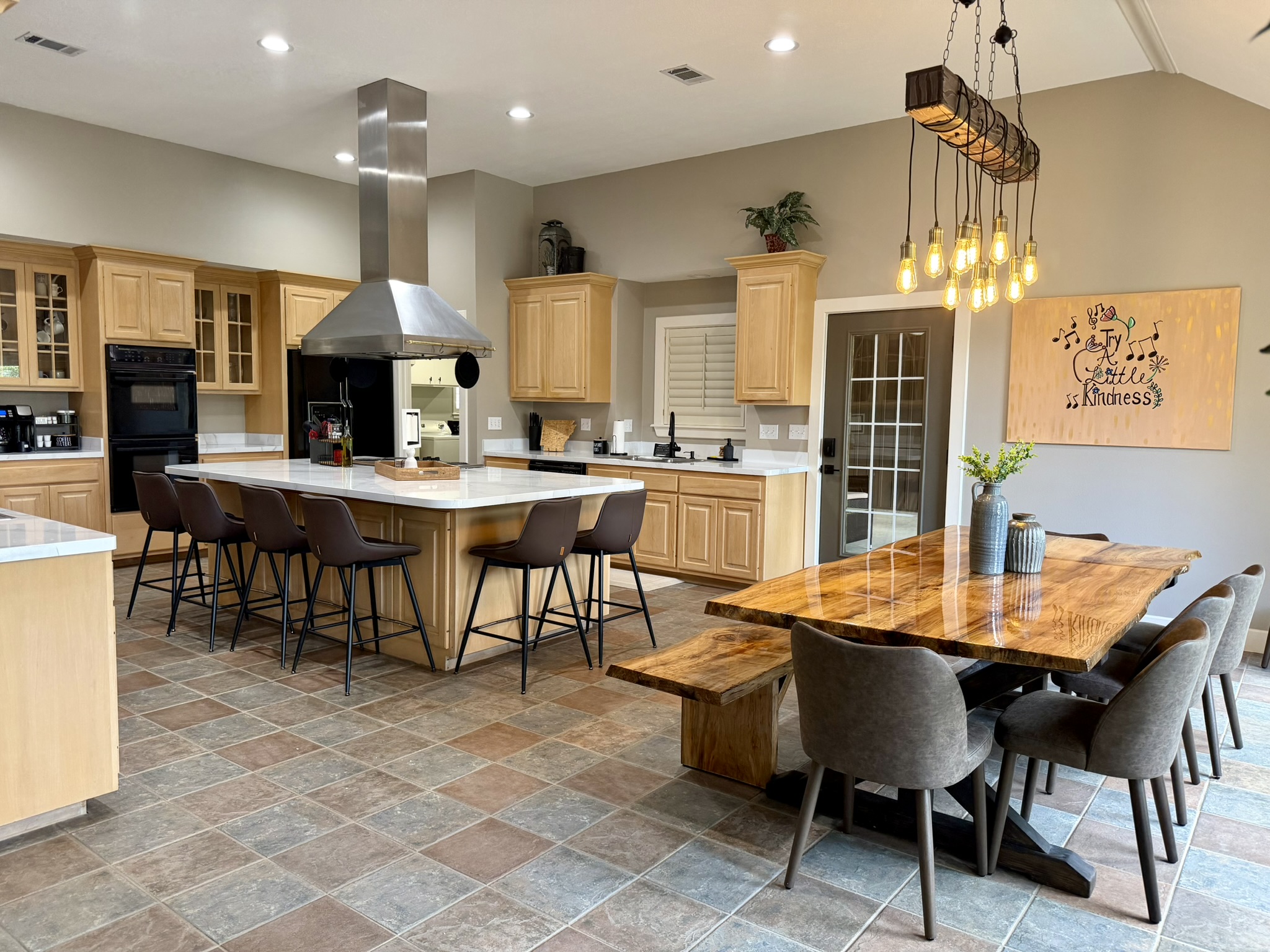 Southern Delight kitchen island with bar seating and sycamore dining table with Edison bulb chandelier